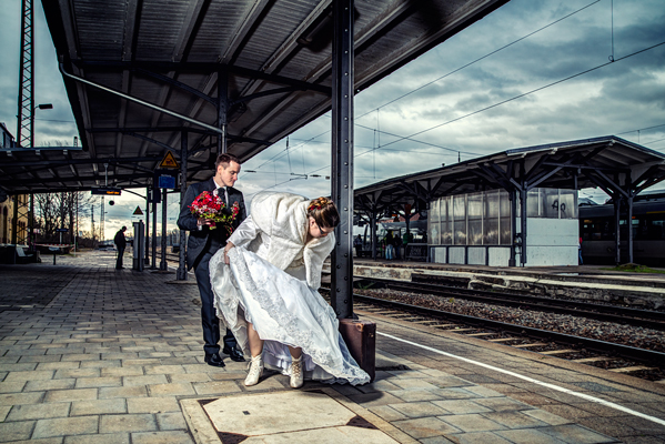 Braut und Bräutigam stehen auf dem Bahnhof