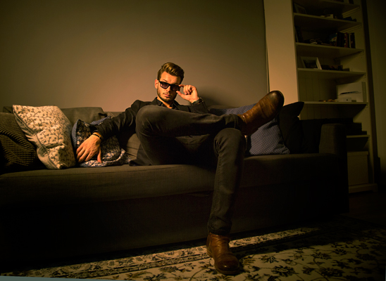 Malemodel mit Sonnenbrille sitzt cool auf Couch